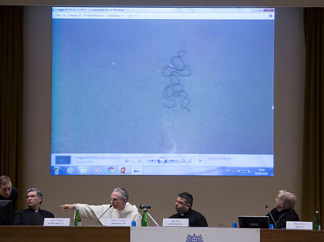 Chefsexorcisterna sitter på scenen under kursen i Rom. Här visar de upp en bild av ett hårstrå, som de menar är format som en mänsklig kropp, som en besatt ska ha kräkts upp. Foto: LINE MØLLER 